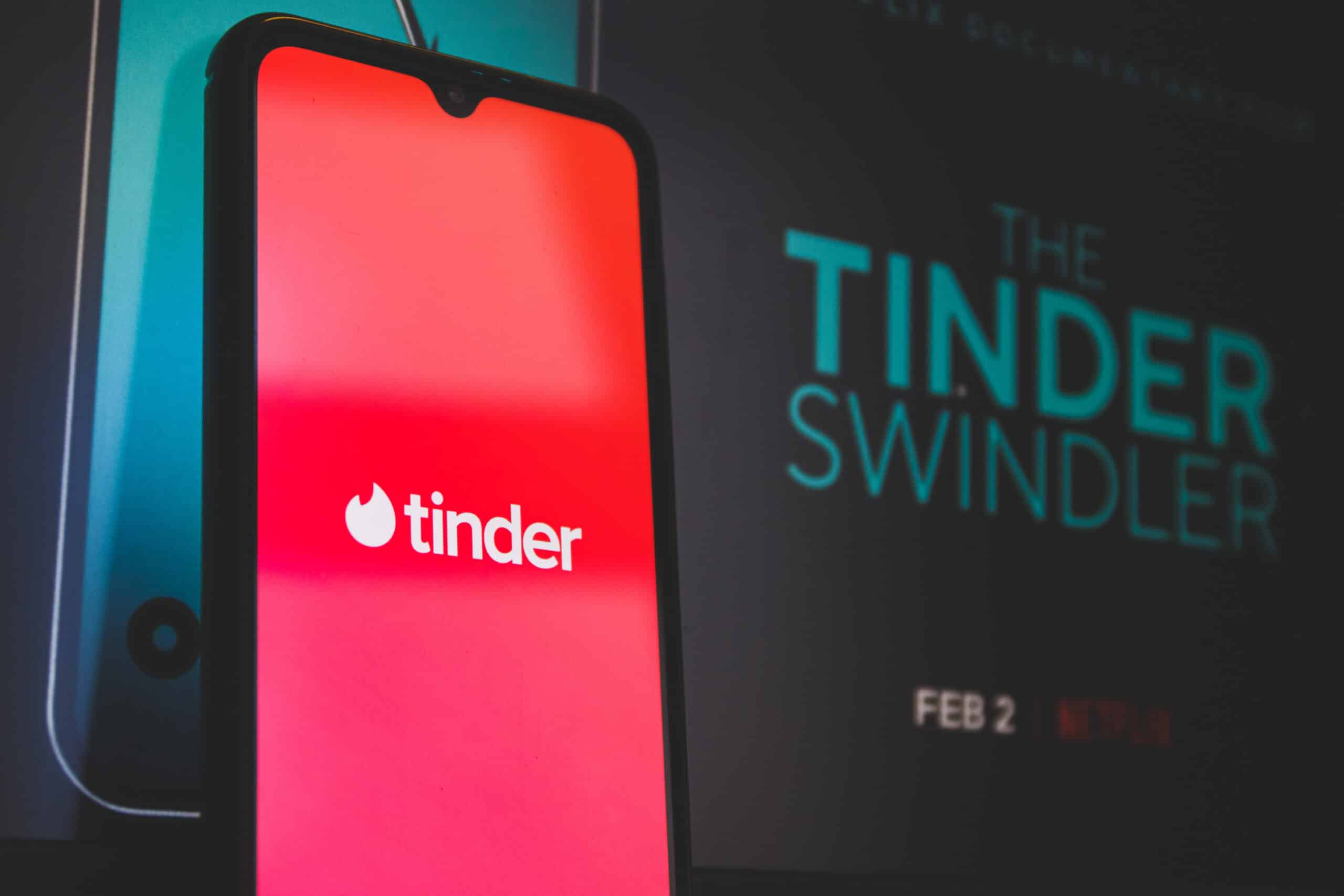 Smartphone with Tinder app open and 'Tinder Swindler' text, highlighting how background checks can help avoid online dating scams.